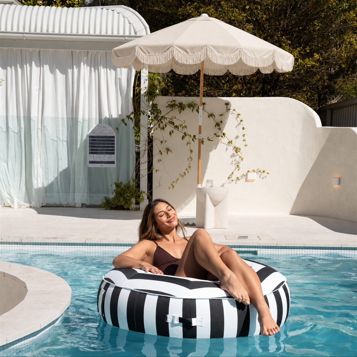 Woman relaxing on a black and white striped Halo Float V2 in the pool